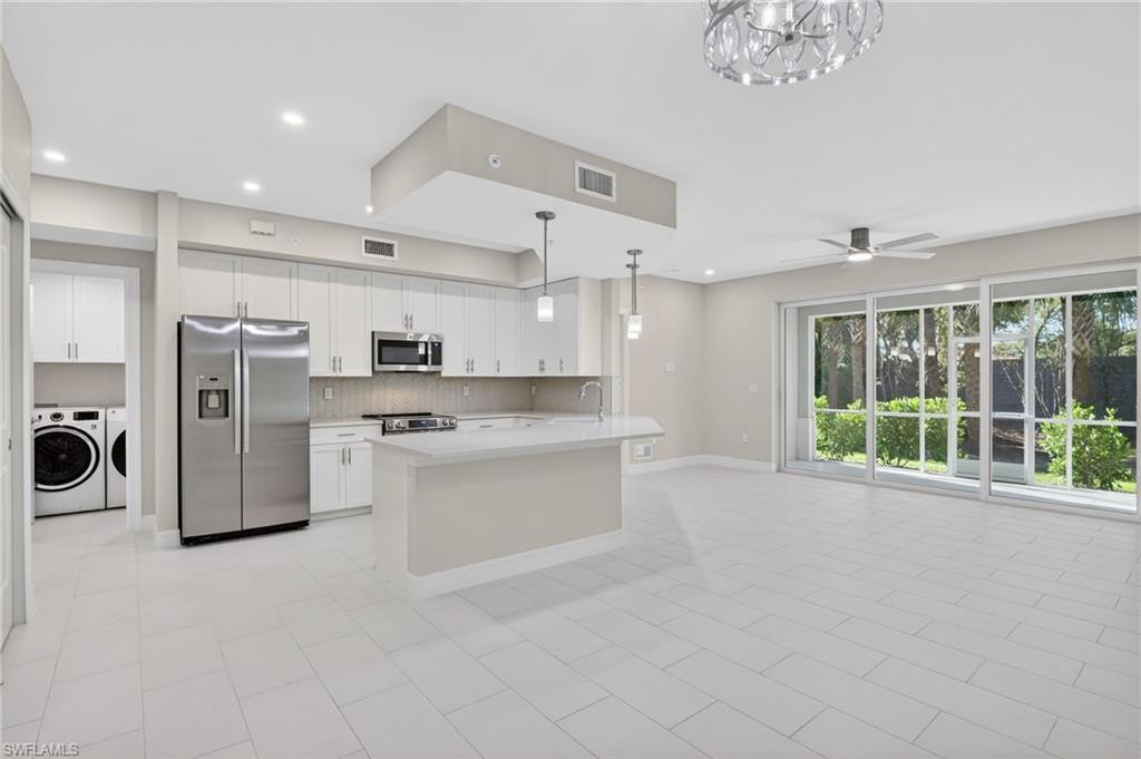 Image 3: Open-concept living space with a contemporary kitchen, large format tile flooring, and extensive sliding glass doors