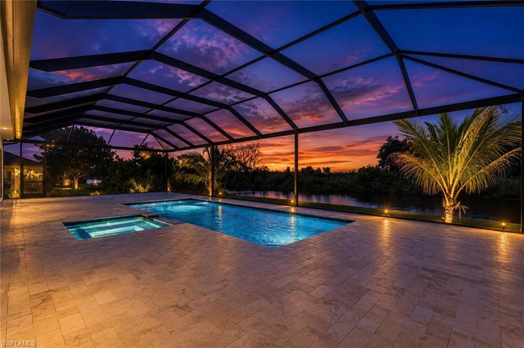 Image 3: Screened outdoor living area featuring a rectangular pool, integrated spa, and expansive paver patio