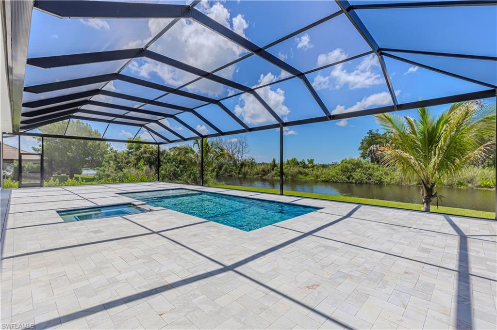 Image 4: Screened outdoor living space featuring an in-ground swimming pool, integrated hot tub, and expansive paver deck