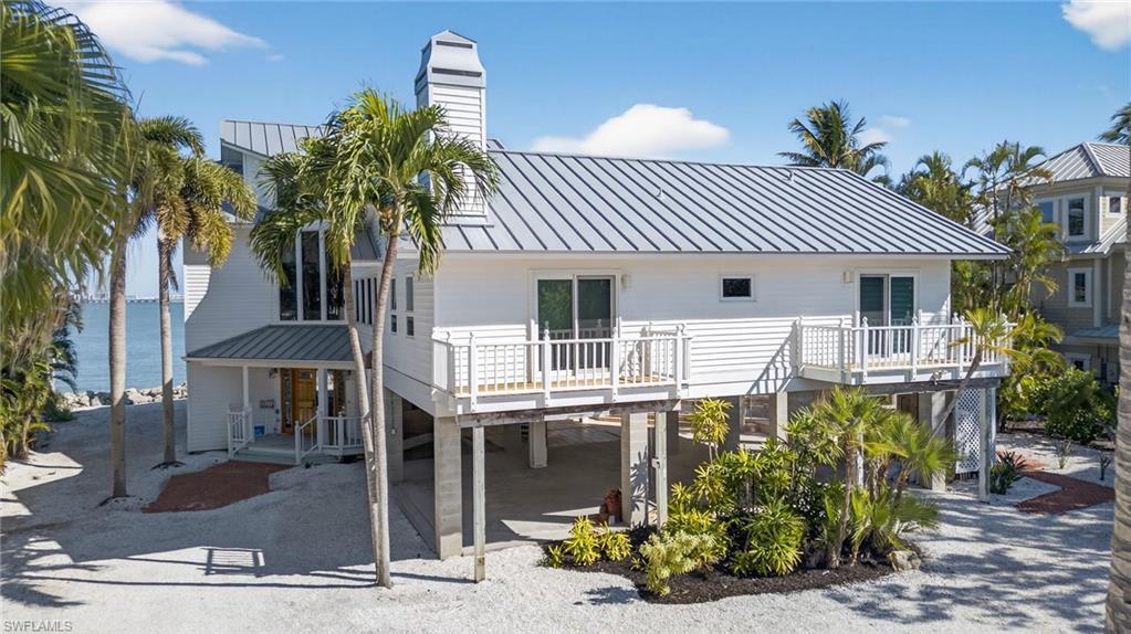 Image 2: Front of property featuring a patio, a metal roof, a standing seam roof, a water view, and a chimney