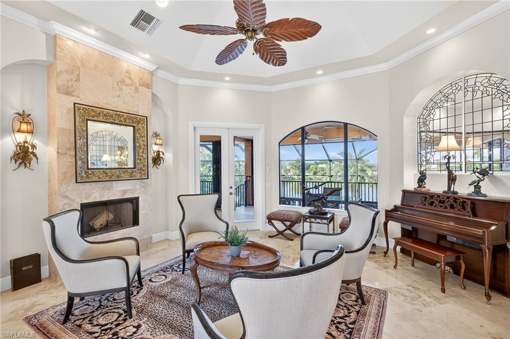 Image 4: Living room featuring ornamental molding, a fireplace, ceiling fan, a high ceiling, and french doors