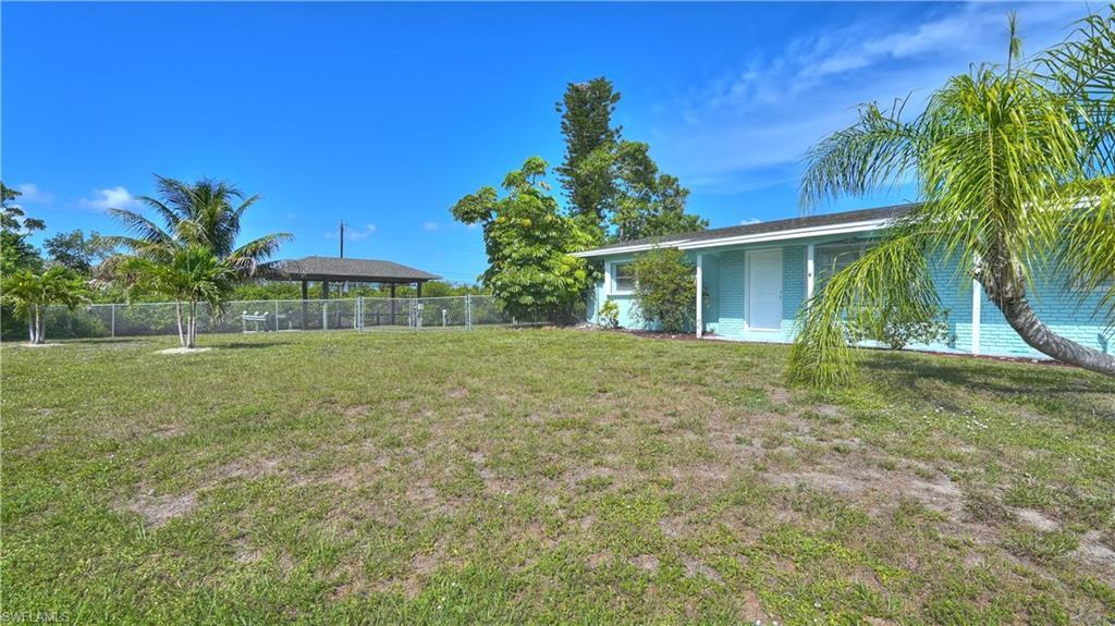 Image 2: Fenced rear yard featuring a covered structure and tropical landscaping