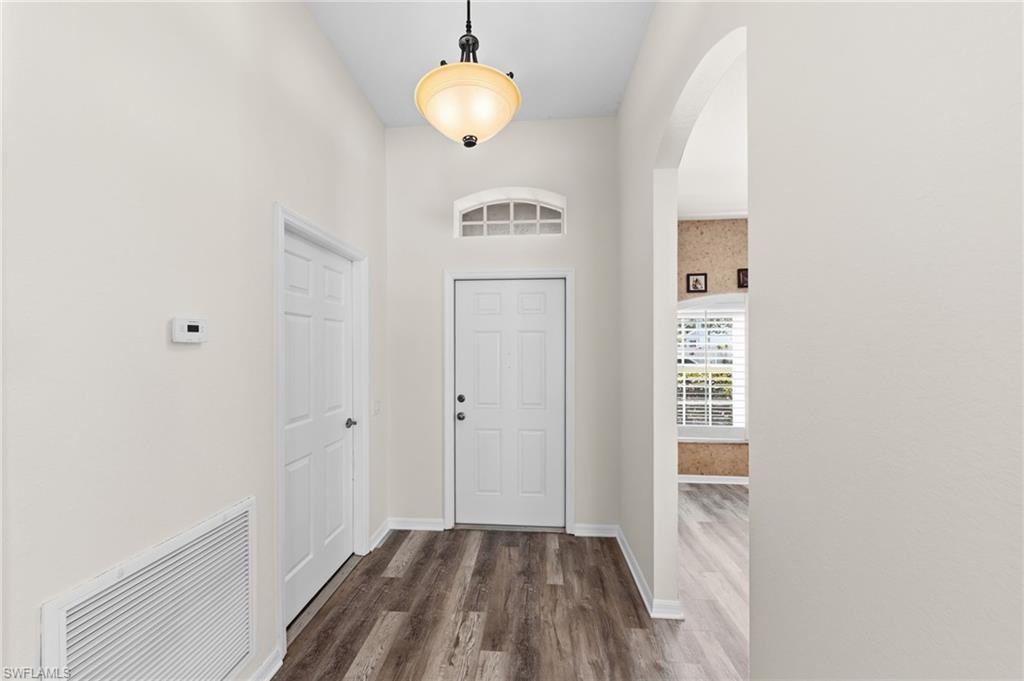 Image 4: Entrance foyer featuring arched walkways, dark wood-style flooring, and a high ceiling
