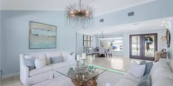 Image 4: Formal living room looking toward double door hurricane impact entry. Multi colored custom lighting on floor.