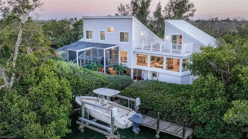 Image 1: Rear view of house featuring boat lift, a lanai, and a sunroom