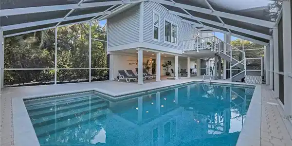 Image 3: Outdoor pool featuring a sunroom, glass enclosure, and a patio area