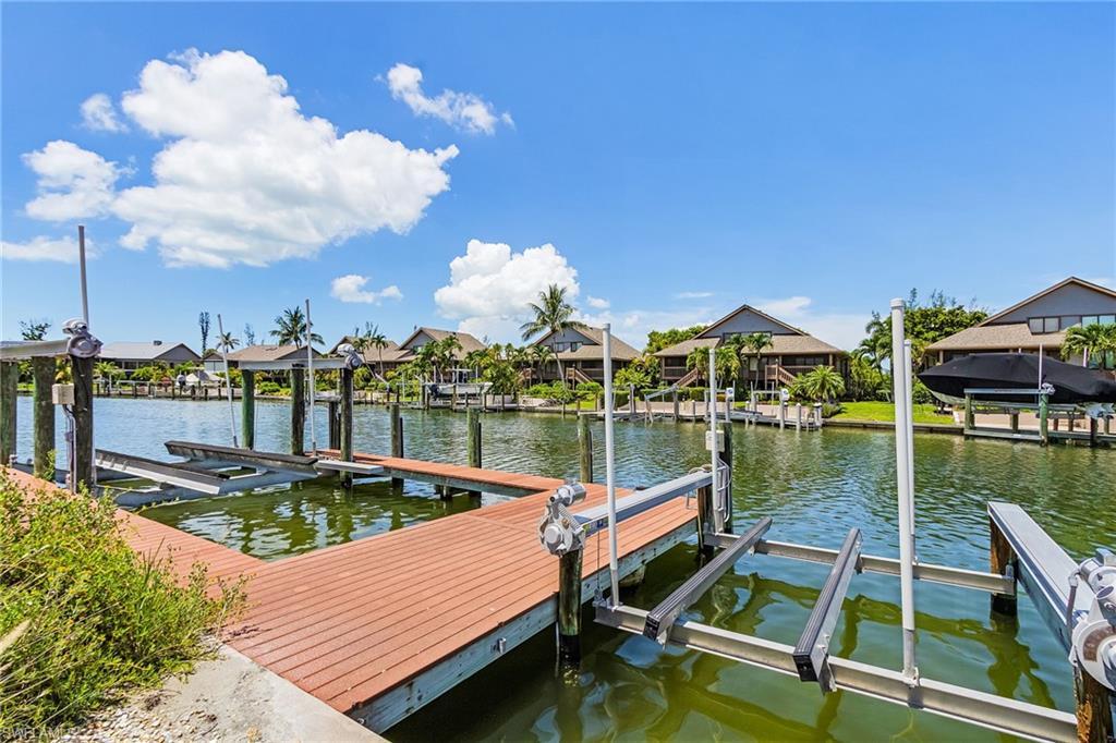 Image 4: Dock featuring boat lift, a residential view, and a water view