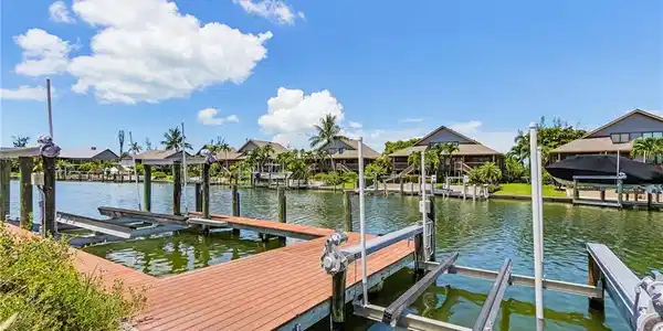 Image 4: Dock featuring boat lift, a residential view, and a water view