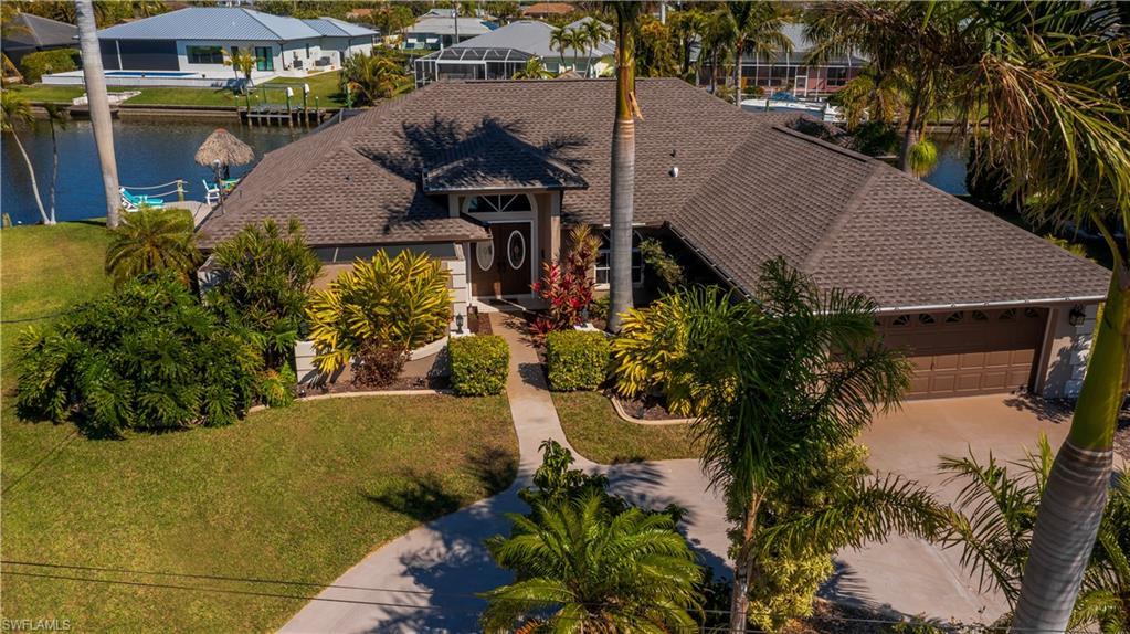 Image 3: View of front facade featuring a front lawn, a water view, an attached garage, and a shingled roof