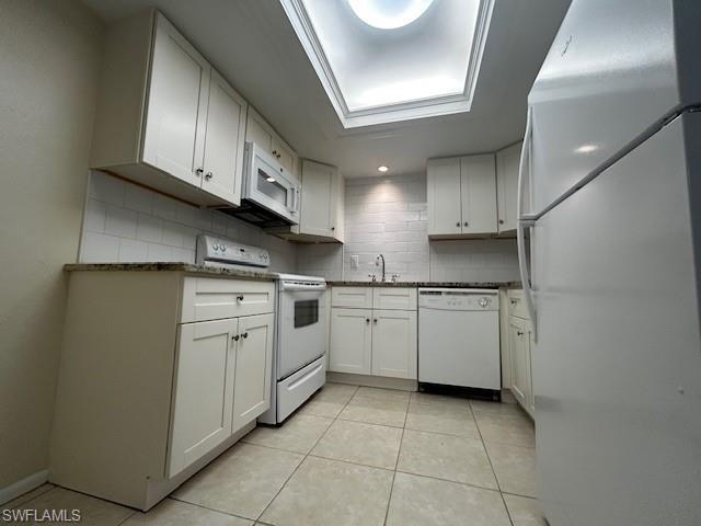 Image 3: Kitchen with white appliances, white cabinets, and light tile patterned floors