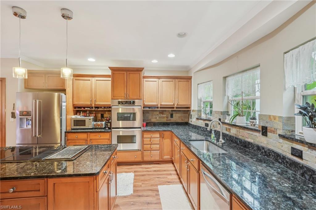 Image 2: Kitchen featuring light wood-type flooring, ornamental molding, decorative backsplash, stainless steel appliances, and a sink