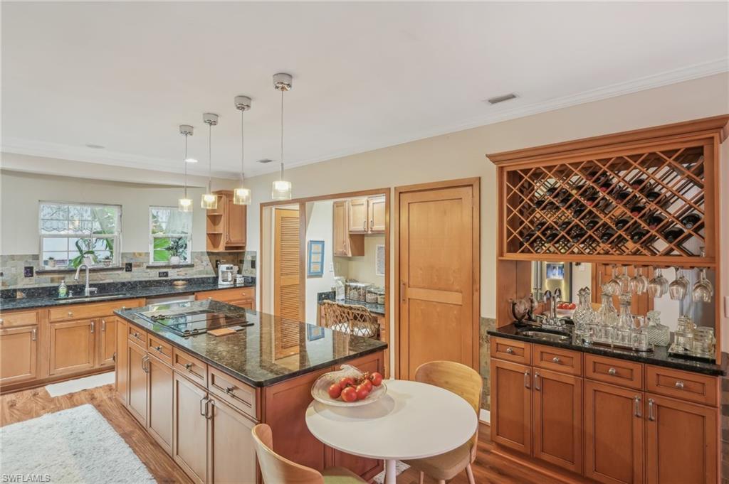 Image 3: Kitchen featuring black electric stovetop, light wood-style flooring, open shelves, a kitchen island, and a sink