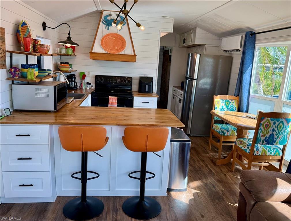 Image 3: Kitchen featuring wood counters, black electric range, range hood, freestanding refrigerator, and dark wood finished floors