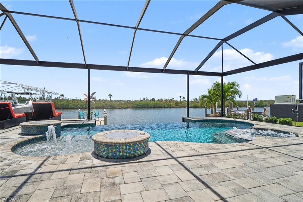 Image 2: The screened outdoor living area features a pool, a hot tub, and an additional water feature, all surrounded by paver decking