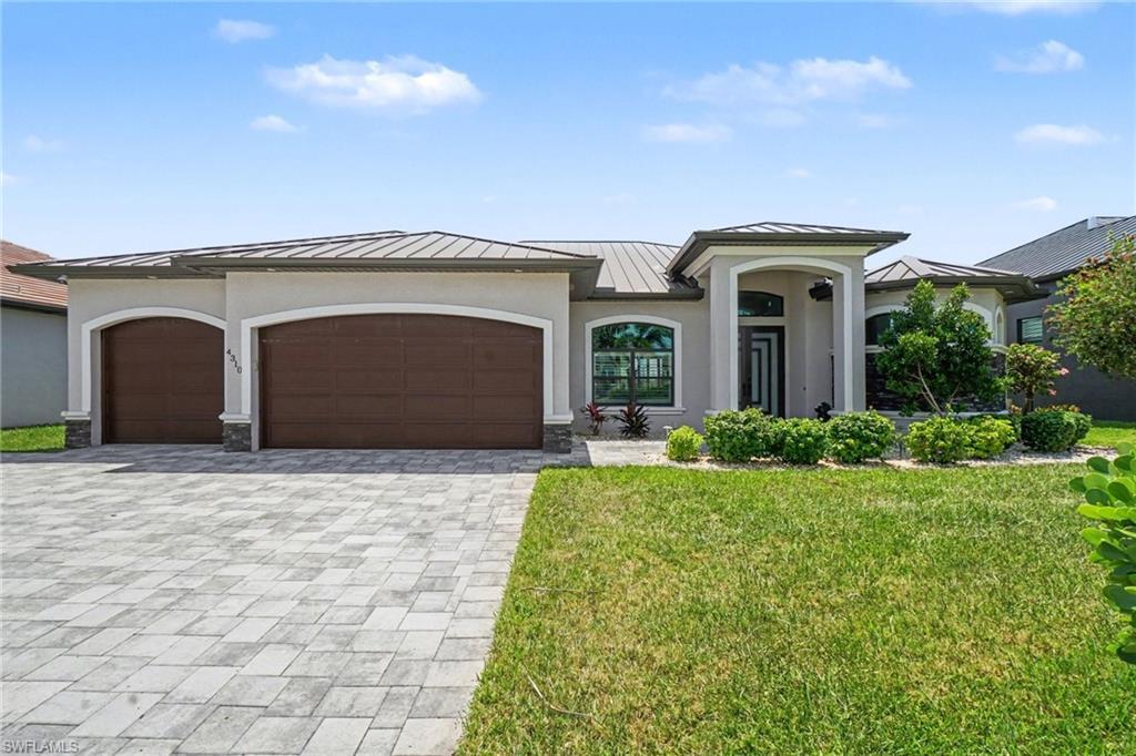 Image 4: The property features a paver driveway, a three-car garage, and a well-maintained lawn with mature landscaping including palm trees