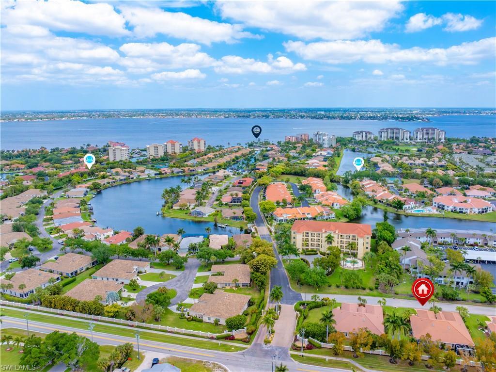 Image 1: Aerial view of the property's community, featuring a large body of water, residential properties with landscaping, and a distant coastline