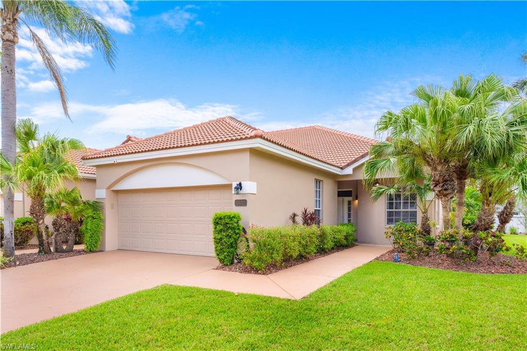 Image 2: The property features a terracotta tile roof, a two-car garage, and a well-maintained lawn with mature palm trees