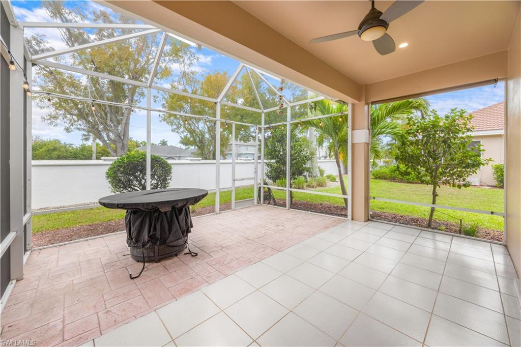 Image 4: Spacious screened patio area featuring both tiled and paved sections, with a ceiling fan and outdoor string lights