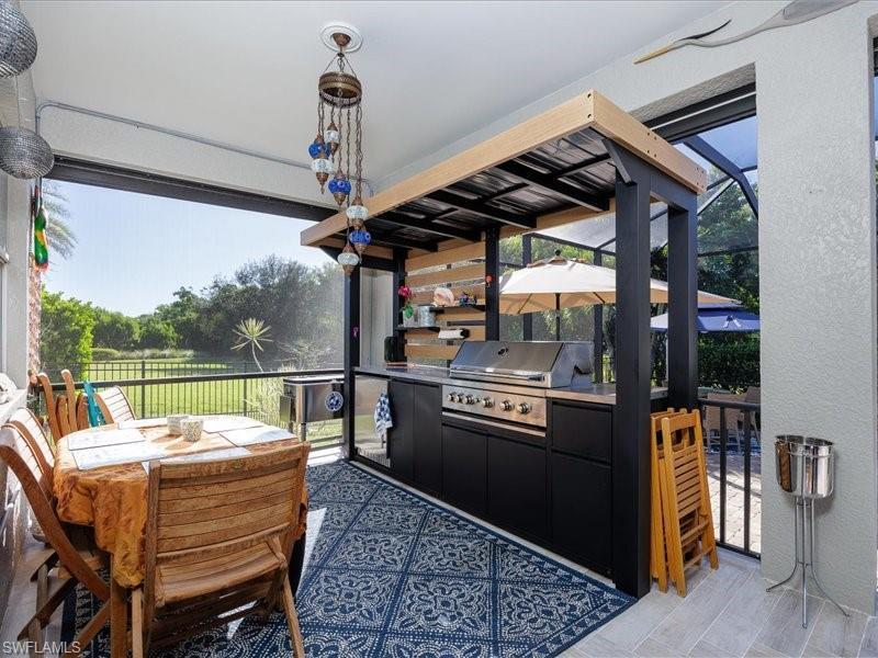 Image 2: Screened lanai featuring a built-in outdoor kitchen with a gas grill and integrated cabinetry