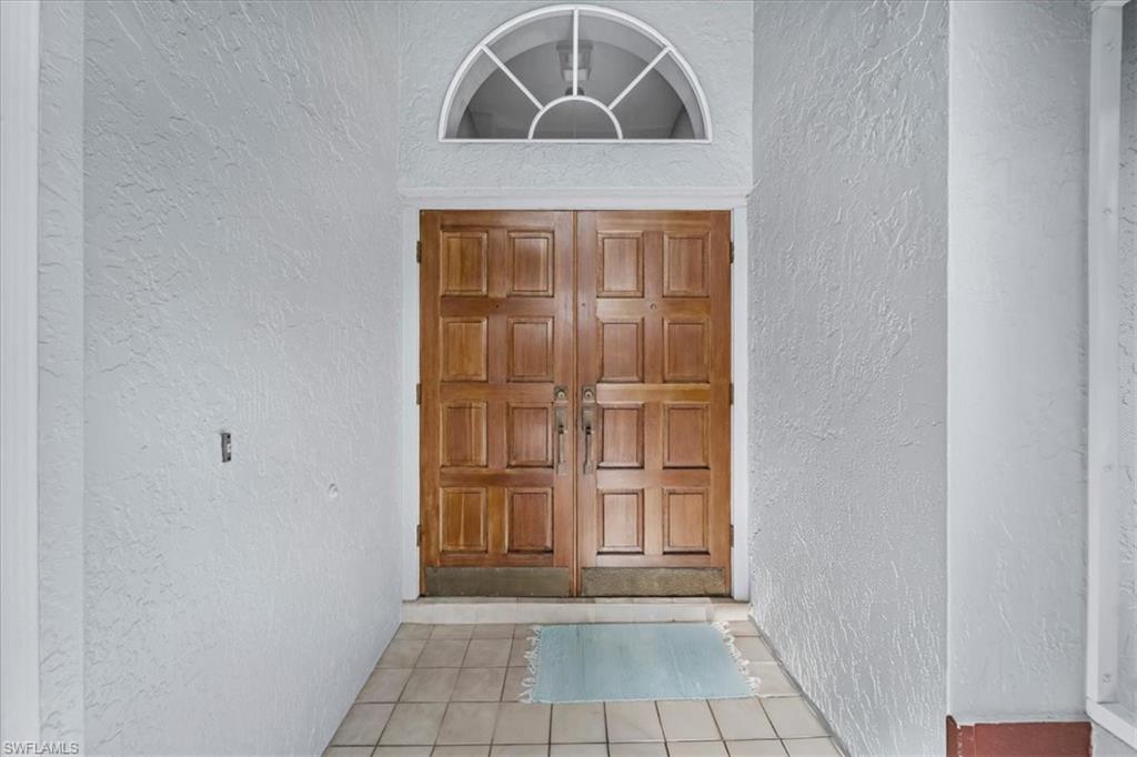 Image 2: Double wooden entry doors with panel details, complemented by a decorative arched transom window