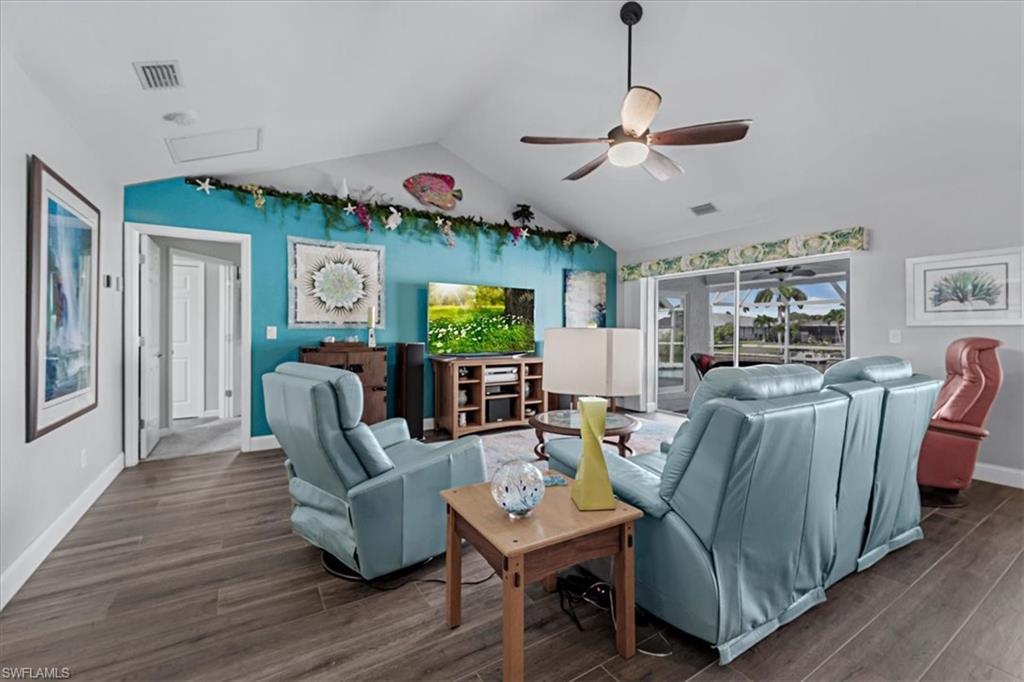 Image 4: Spacious living area featuring vaulted ceilings, wood look Tile flooring, and a ceiling fan with integrated lighting