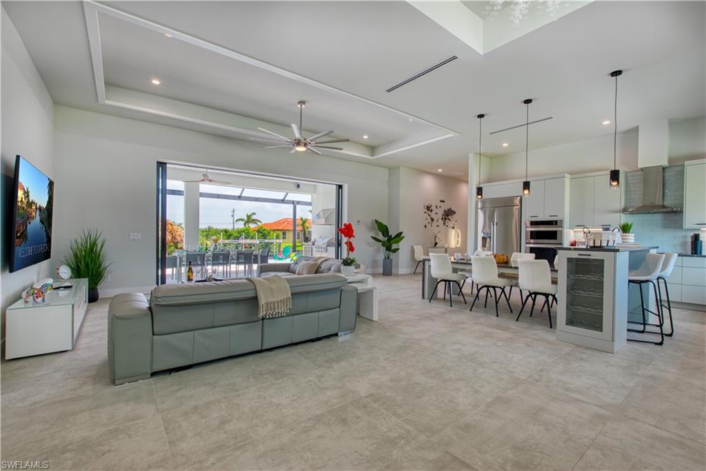 Image 3: Open-concept living space with large format tile flooring and a tray ceiling