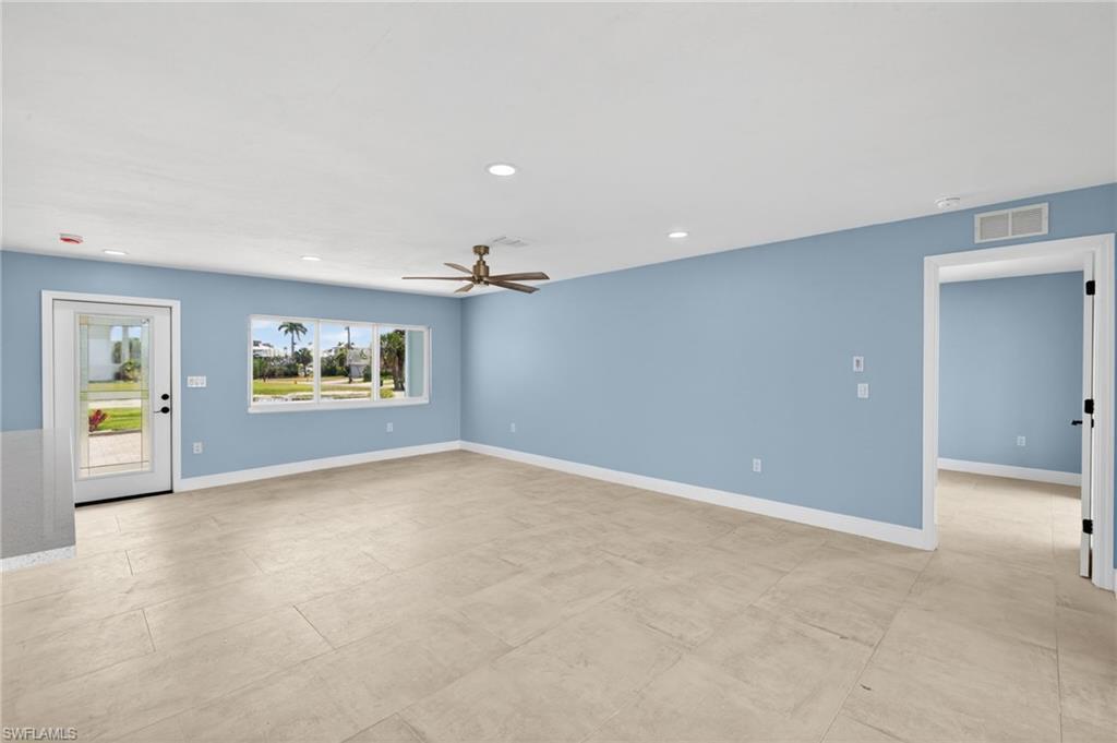 Image 3: Spacious interior with neutral tile flooring, recessed lighting, a modern ceiling fan, and a large window overlooking exterior landscaping