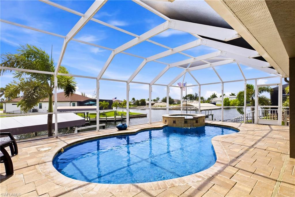 Image 4: Screened lanai featuring a freeform pool, integrated spa, and spacious paver deck