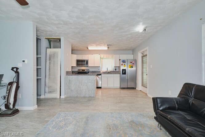 Image 3: Living room featuring baseboards and a textured ceiling