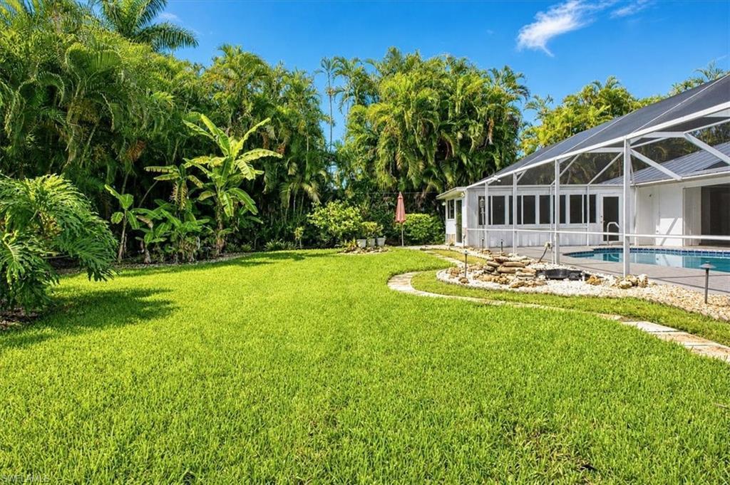 Image 4: Lots of backyard grassy area beyond the pool deck/cage