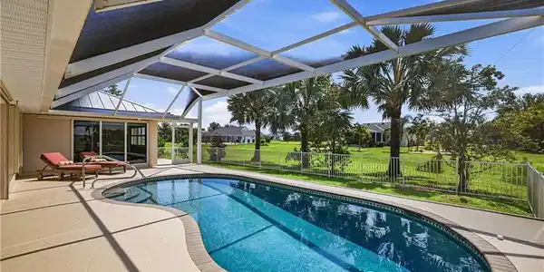 Image 2: Resort-Style Lanai with Heated Swimming Pool and Retractable Storm-Smart Shade SystemThis expansive covered lanai showcases a resort-inspired outdoor living space anchored by a lagoon-shaped heated swimming pool with tanning ledge