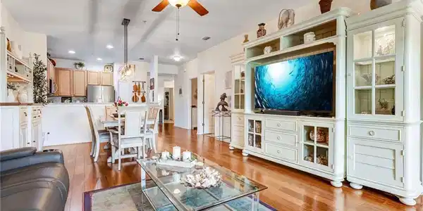 Image 3: Wood-finish flooring throughout, with a ceiling fan featuring integrated lighting