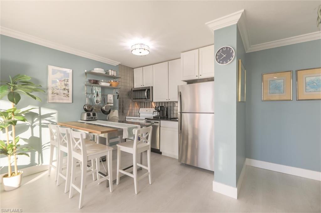 Image 3: Kitchen featuring decorative backsplash, stainless steel appliances, light hardwood / wood-style floors, crown molding, and white cabinets