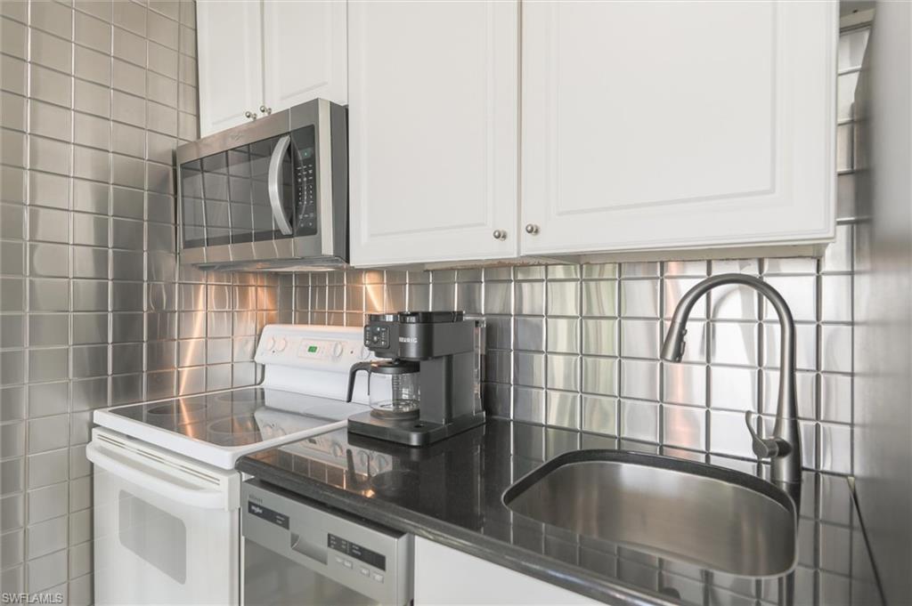 Image 4: Kitchen with decorative backsplash, sink, white range with electric cooktop, dishwashing machine, and white cabinets