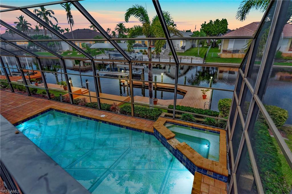 Image 3: Pool at dusk with an in ground hot tub and a water view