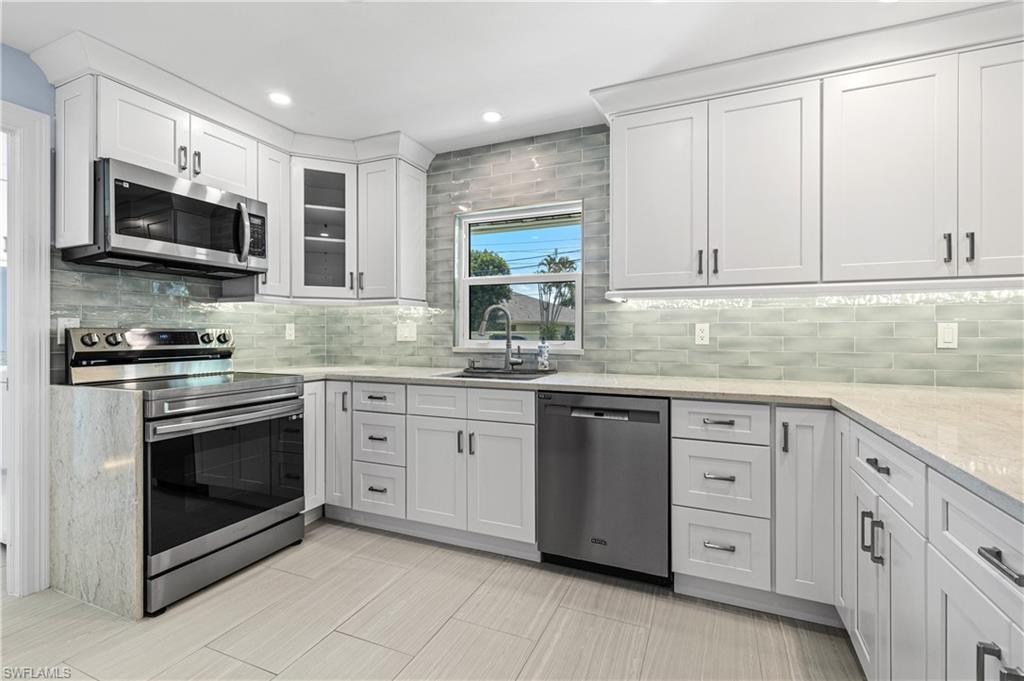 Image 2: Kitchen featuring appliances with stainless steel finishes, backsplash, white cabinets, light stone counters, and recessed lighting