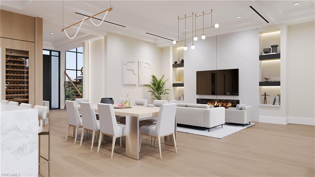 Image 4: Architectural rendering. Plans and finishes can be customized. Dining area featuring light wood finished floors, beverage cooler, a fireplace, stairway, and recessed lighting.