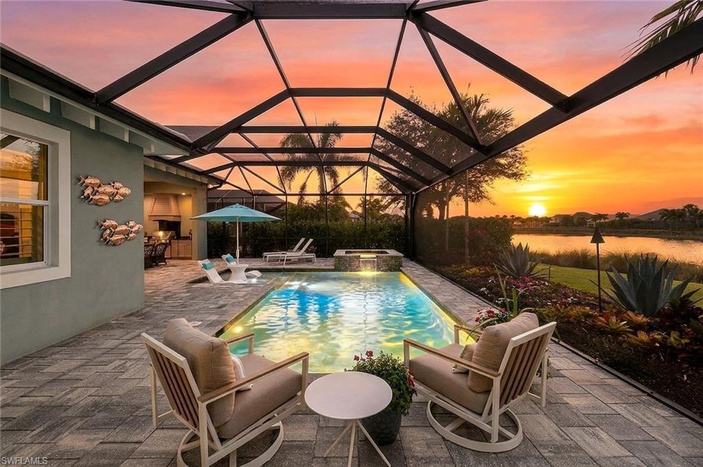 Image 2: Pool at dusk featuring a pool with connected hot tub, a patio area, a lanai, and a sunroom