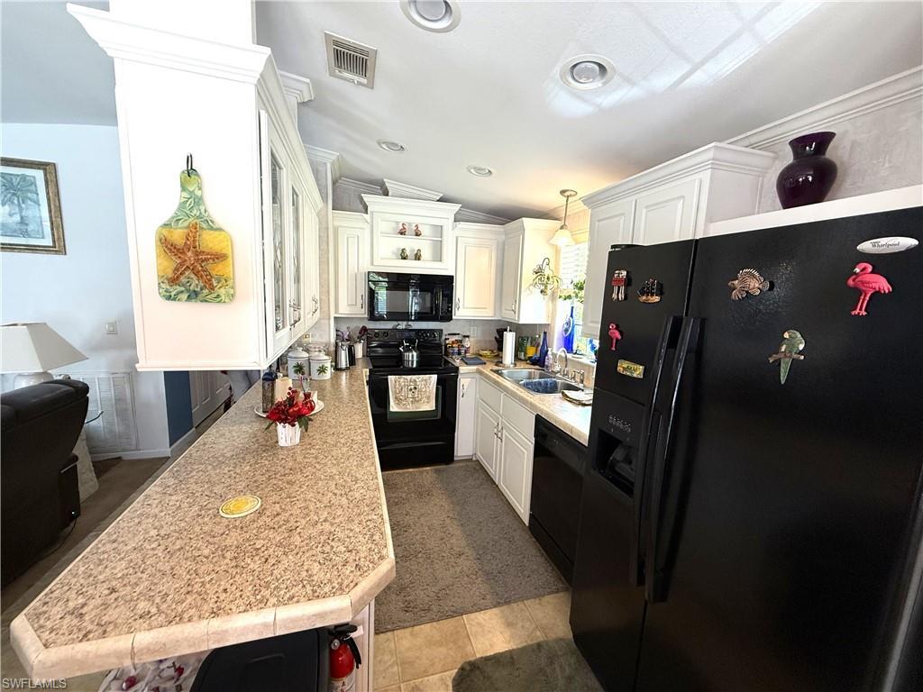 Image 3: Kitchen featuring black appliances, white cabinets, and lofted ceiling