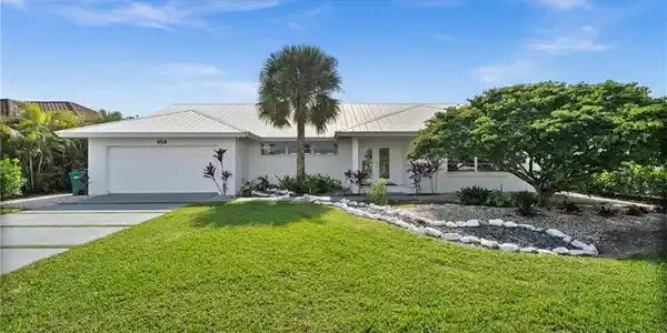 Image 3: The property features a well-maintained lawn, a paved driveway leading to a garage, and a white exterior
