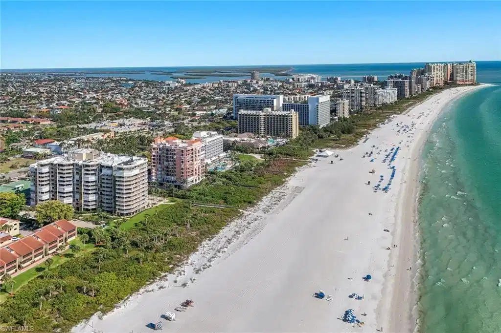 Image 1: This aerial view highlights the expansive white sandy beach and the clear turquoise water