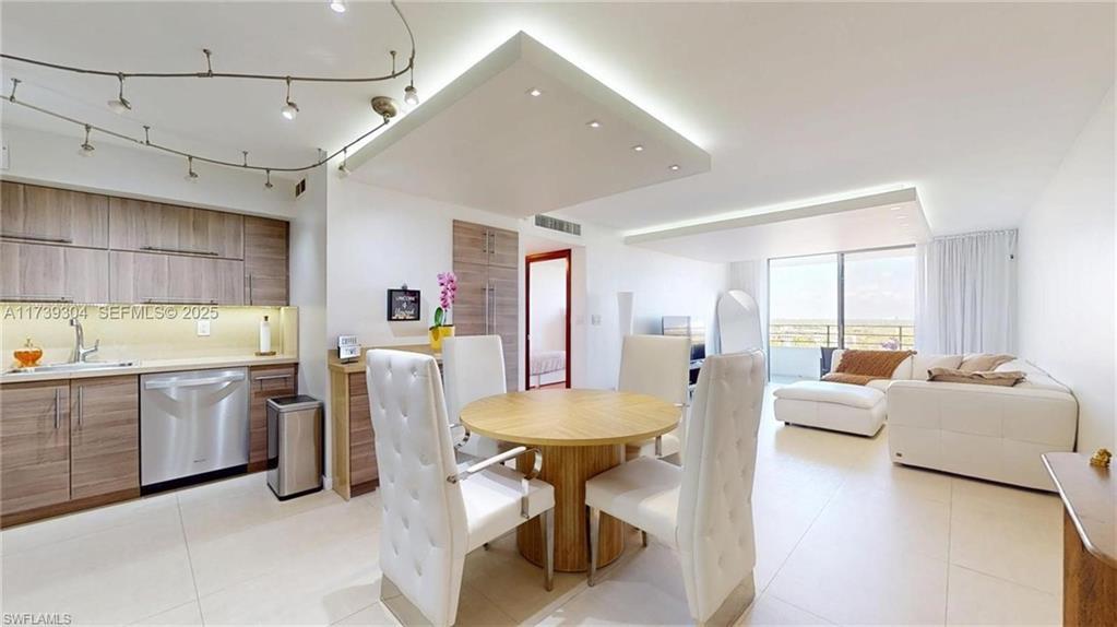 Image 3: Open-concept living space featuring a modern kitchen with wood-finish cabinetry, stainless steel dishwasher, and track lighting