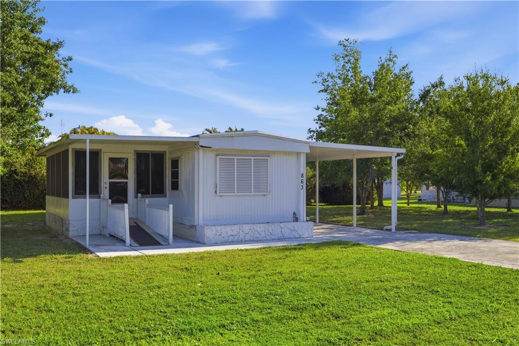 Image 2: Single-story residence featuring a screened porch, covered carport, and a concrete driveway