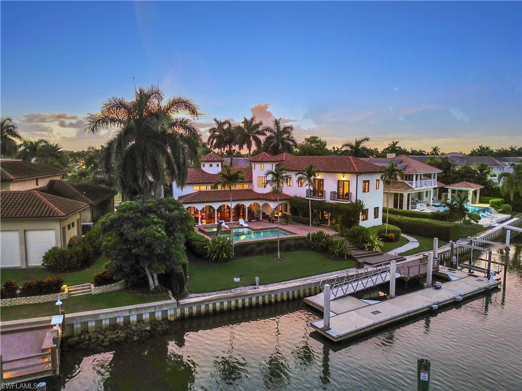 Image 2: Mediterranean-style residence featuring a terracotta tile roof, white stucco exterior, arched covered patio, private swimming pool, and a multi-slip dock with a boat lift