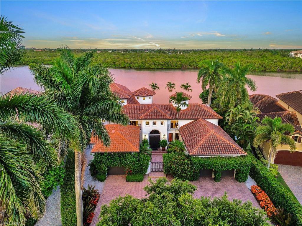 Image 3: Mediterranean-style residence featuring a terracotta tile roof, white stucco exterior, and lush tropical landscaping