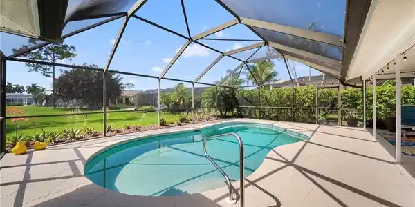 Image 4: Screened-in outdoor pool featuring an irregular shape, integrated stairs, and a stainless steel grab rail