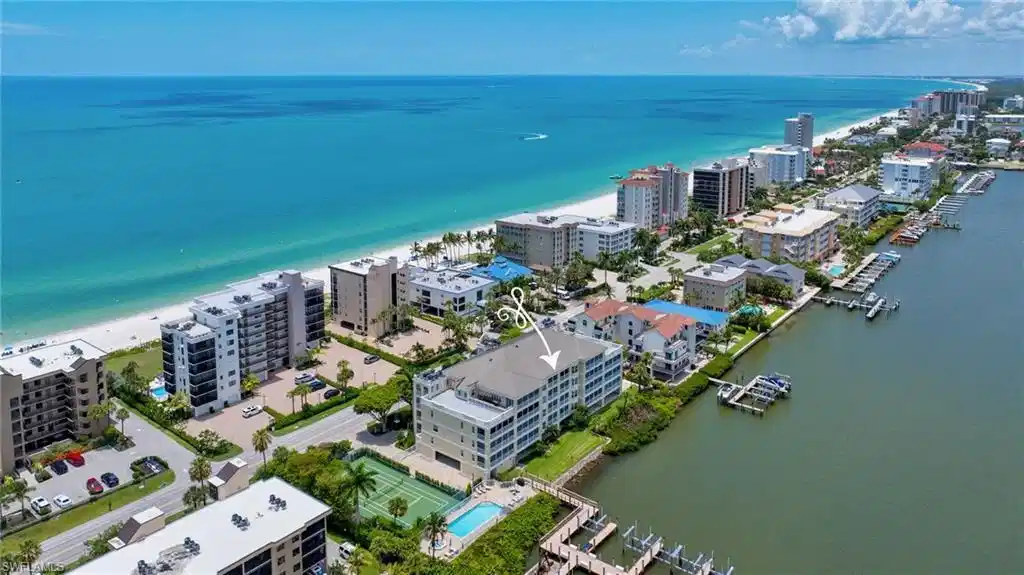 Image 1: Four-story residential building with multiple private balconies, situated between a coastal beach and a waterway