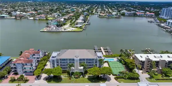 Image 3: Waterfront community with multiple buildings, private boat docks, tennis court, and swimming pool