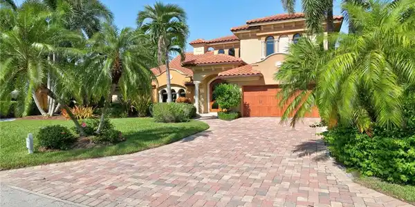 Image 3: Spanish Colonial-style residence featuring a terracotta tile roof, arched entryways, and a warm stucco exterior