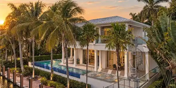 Image 2: Waterfront residence featuring a private dock, expansive swimming pool, spiral staircase, upper-level balcony with glass railings, and mature palm trees
